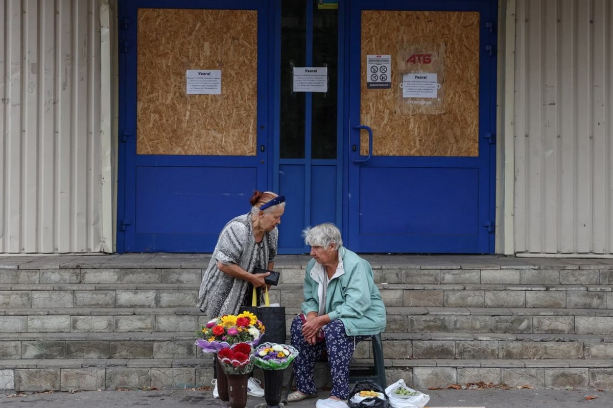 Жінки біля зачиненого супермаркету продають квіти й городину. У Покровську зачинені всі великі супермаркети і ТЦ, працюють лише невеличкі продуктові магазини